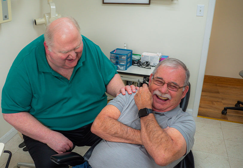 Dr. Monsman laughing with patient in dental chair
